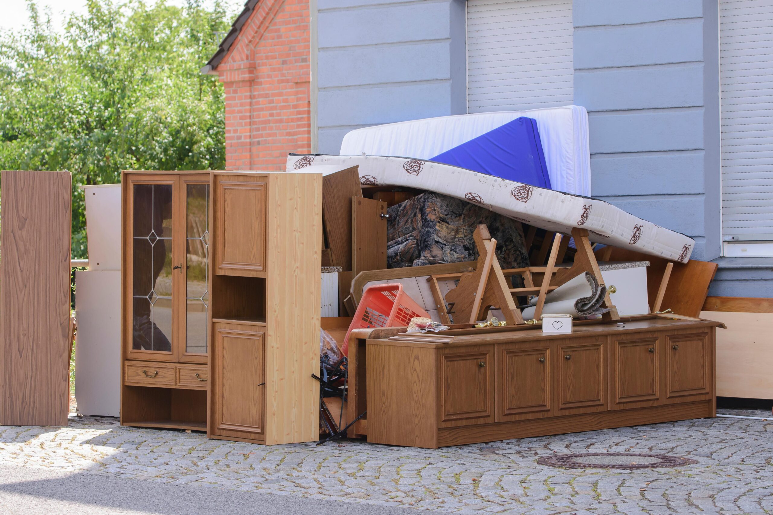 Aufgestapelte Möbel und Einrichtungsgegenstände vor einem Mehrfamilienhaus in Wesseling.